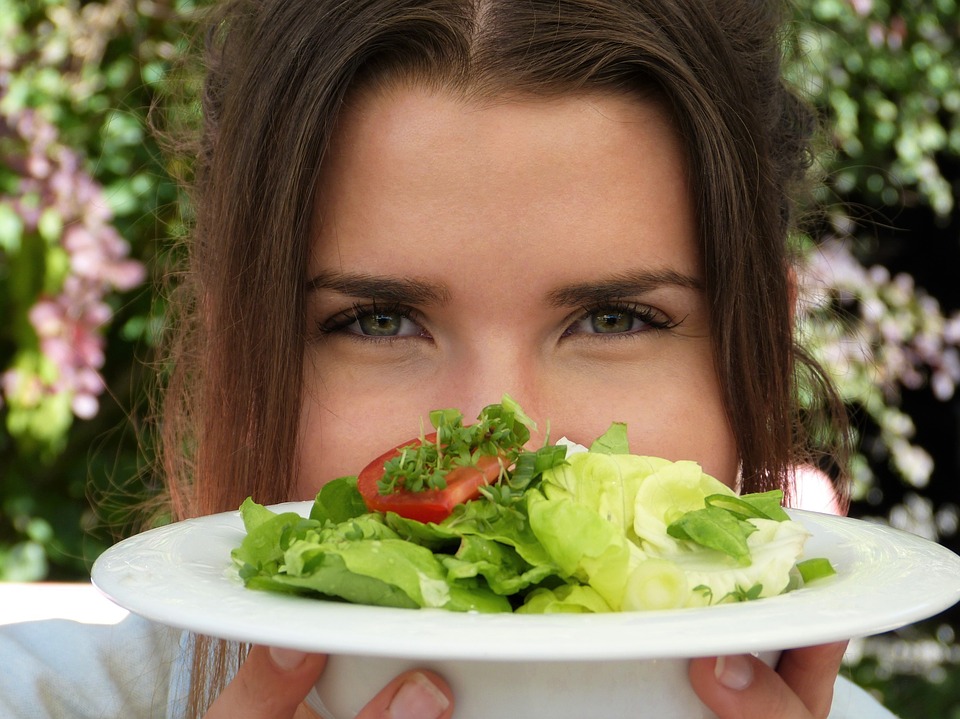 woman holding a plate of salad as her raw vegan diet