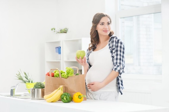 a pregnant woman standing in the kitchen raw vegan pregnancy