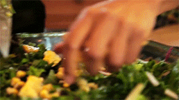 hand sprinkling corns on a bowl of vegetable salad