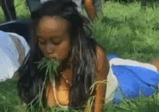 woman lying face down on the ground eating grass